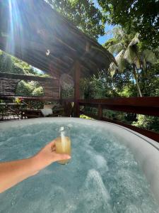 a person holding a drink in a hot tub at Lodge Ti Zaboka , SPA Privatif in Les Abymes