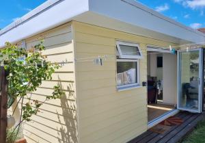 a yellow tiny house with a porch at The Witterings Bed and Breakfast in Chichester
