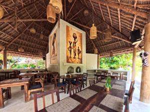 a restaurant with tables and chairs and a large painting on the wall at Paje By Night Bungalows in Paje
