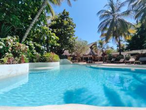 a swimming pool in a resort with palm trees at Paje By Night Bungalows in Paje