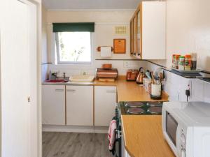 a kitchen with white cabinets and a stove top oven at Noddfa in Newcastle Emlyn