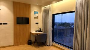 a hotel room with a large window with a desk and a chair at hotel midas in Sāgar