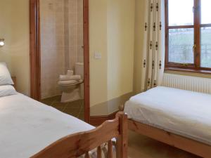 a bedroom with two beds and a bathroom with a toilet at Elderberry House in Kelly