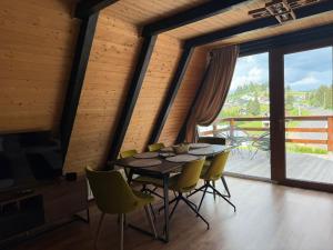 a dining room with a table and yellow chairs at Cabane A-frame CeziAde Tihuta in Piatra Fantanele