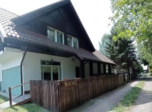a house with a wooden fence in front of it at Biały Dom - Pokoje in Wejsuny