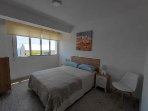 a bedroom with a bed and a chair and a window at Pedra Pateira 2 in Ribeira