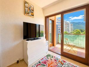 a living room with a television and a balcony at Urban Nest Geneva Tramway in Gaillard +4 photos
