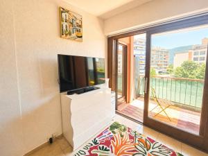 a living room with a flat screen tv and a balcony at Urban Nest Geneva Tramway in Gaillard