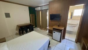 a hotel room with two beds and a desk and a television at CRCN - Golden Dolphin Grand Hotel in Caldas Novas