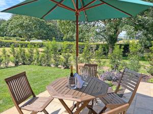 a wooden table with a bottle of wine and an umbrella at The Dairy - Uk50427 in Malton