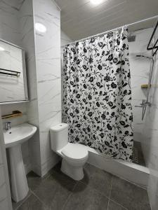 a bathroom with a toilet and a shower curtain at Raduga West in Koshkolʼ