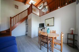 a living room with a table and a staircase at Logis Hotel & Restaurant Bergeret Sport in Hendaye
