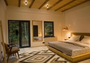 a bedroom with a bed and a chair and windows at "The Nest" Premium Mountain Lodge with Alpine retreat & Sauna in Vanadzor