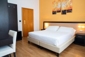 a bedroom with a white bed and a wooden floor at Albergo San Lorenzo in Grosseto