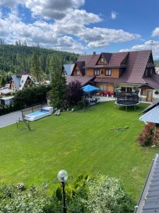 a large yard with a large house with a pool at Domki Chatka U Staszka in Małe Ciche