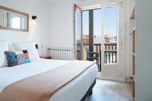 a bedroom with a large bed and a balcony at Logis Hotel & Restaurant Bergeret Sport in Hendaye