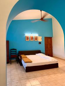 a bedroom with a bed and a blue wall at Bijou Guest House in Baga