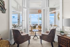 a living room with chairs and a table with a view of the ocean at Beach Front Guest House in Eastbourne