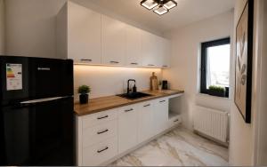 a kitchen with white cabinets and a black refrigerator at LWS Apartments in Dej