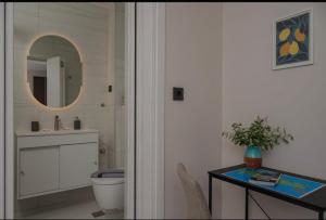 a bathroom with a sink and a toilet and a mirror at Dimitra Suites in Pythagoreio