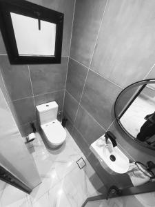 a bathroom with a toilet and a sink and a mirror at La Casa Residence in Dakar