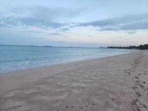 a beach with footprints in the sand and the ocean at Trinco salli beach resort in Trincomalee