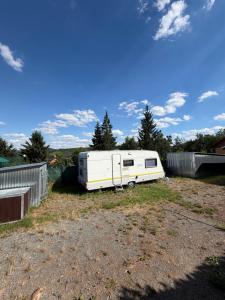 a white trailer parked in a field in a yard at Karavan Hrdlička in Čím