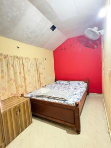 a bedroom with a bed and a red wall at Gopetown Homestay in Mudigere