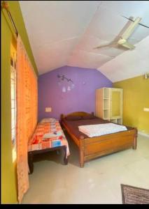two beds in a room with a purple wall at Gopetown Homestay in Mudigere