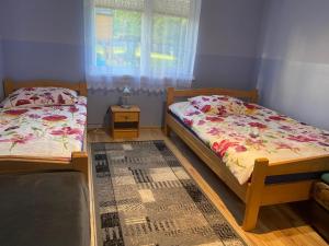 two twin beds in a room with a window at Łabudówka in Polańczyk