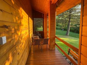 a porch of a wooden cabin with chairs on it at Łabudówka in Polańczyk