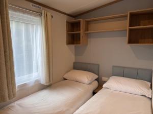 two beds in a small room with a window at Luxury Lodge in Beverley