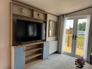 a living room with a tv and a sliding glass door at Luxury Lodge in Beverley