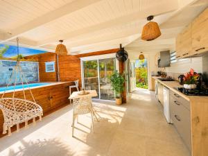 a kitchen with a tub and a table and chairs at Filao Cottage Bungalow avec Piscine Privée Proche plages in Sainte-Rose
