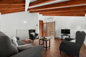 a living room with a couch and two chairs and a tv at Can Mayol in Fornalutx +18 photos