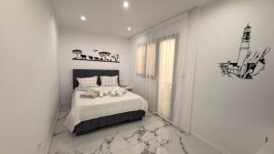 a white bedroom with a bed with two pillows at Victory in Alicante