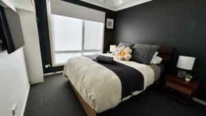 a bedroom with a bed with a teddy bear on it at Coastal Tones - Designer Beach house - Pets Welcome - Huge Yard - Walk to Beach in Cowes