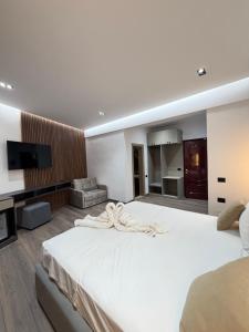 a bedroom with a large white bed and a television at Hotel Tragjasi in Orikum