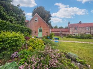 a brick house with a green door in a yard at The Other House in Briston