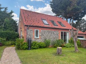 a small brick house with a red roof at The Other House in Briston