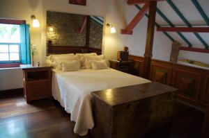 a bedroom with a large bed with white sheets at Casa Beijaflor in Paraty