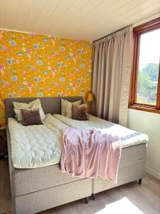 a bed in a room with a flower wall at Seaside Stay Haverdal in Haverdal +15 photos
