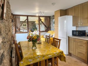 a kitchen with a table with a vase of flowers on it at Mum's Cottage - Uk52136 in Henwood +10 photos