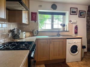 a kitchen with a sink and a washing machine at Mum's Cottage - Uk52136 in Henwood