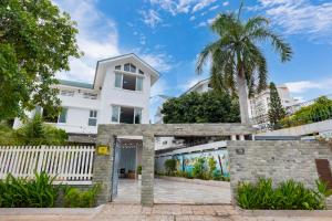 a white house with a palm tree at Kegotel Luxury Villa - Bãi Tắm Long Cung in Vung Tau