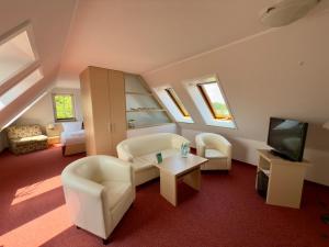 a living room with white furniture and a flat screen tv at Hotel & Restaurant Waldblick in Pulsnitz