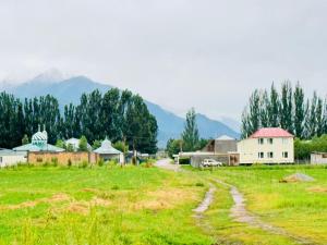 a dirt road in a field with mountains in the background at AI-NUR guest house in Shabdan