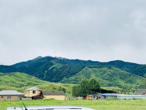 a car parked in a field with mountains in the background at AI-NUR guest house in Shabdan +3 photos