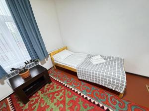 a small bedroom with a bed and a table at AI-NUR guest house in Shabdan