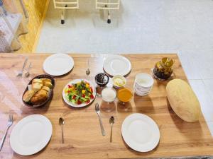 a wooden table with white plates and utensils and food at AI-NUR guest house in Shabdan